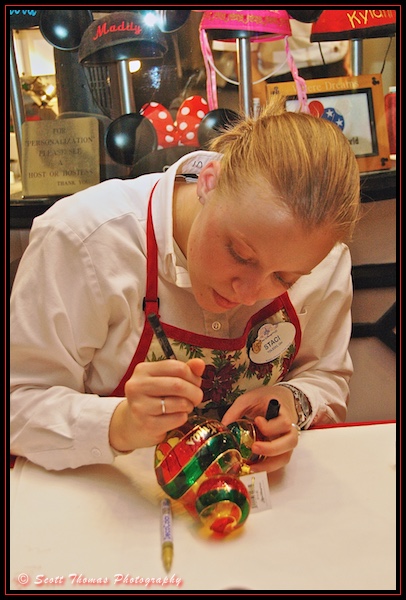 Disney's Hollywood Studios cast member personalizes a Christmas tree ornament for a guest, Walt Disney World, Orlando, Florida