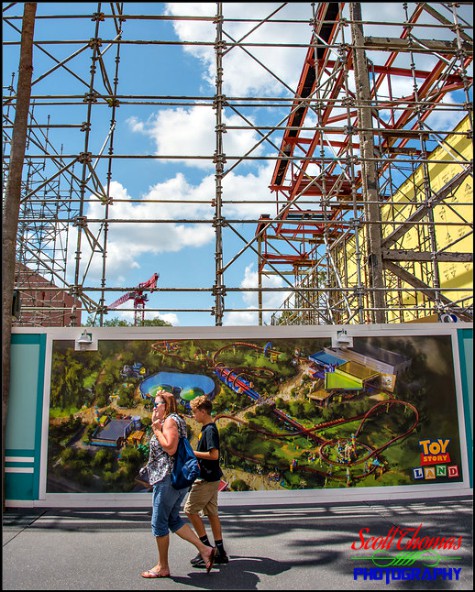People walking past the poster on a construction wall of the future Toy Story Land on Pixar Place at Disney's Hollywood Studios, Walt Disney World, Orlando, Florida