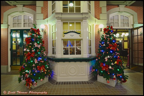 Main Street Railroad Station office framed by a pair of Christmas trees in the Magic Kingdom, Walt Disney World, Orlando, Florida