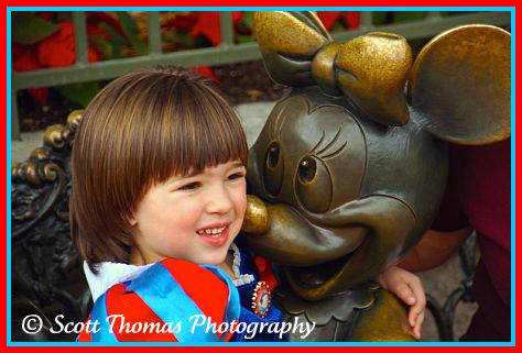 A girl sitting in Minnie Mouse's lap in the Magic Kingdom, Walt Disney World, Orlando, Florida.